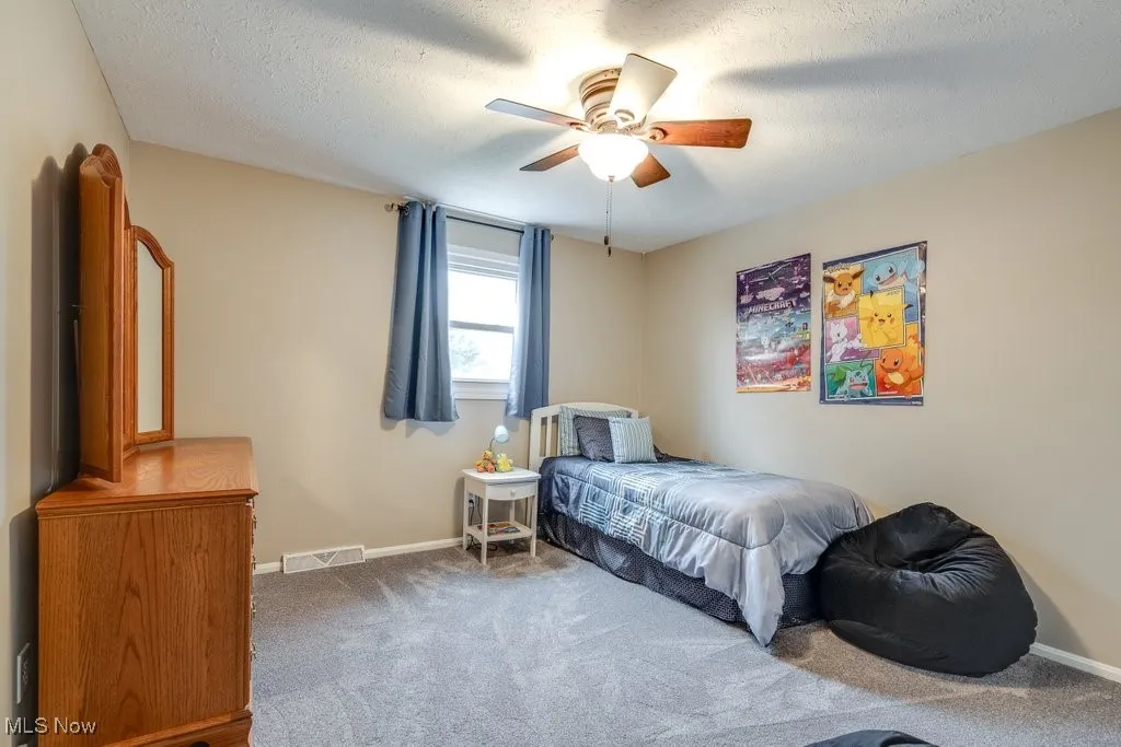 Bedroom with carpet, a ceiling fan, and a textured ceiling