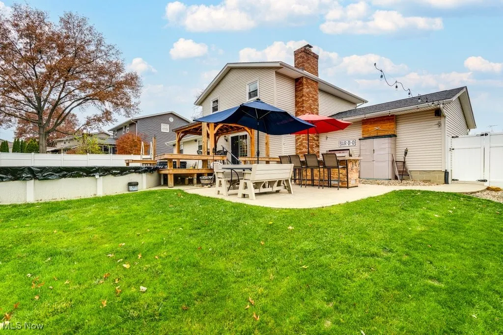 Back of house with a gazebo, a fenced backyard, a patio, and a chimney