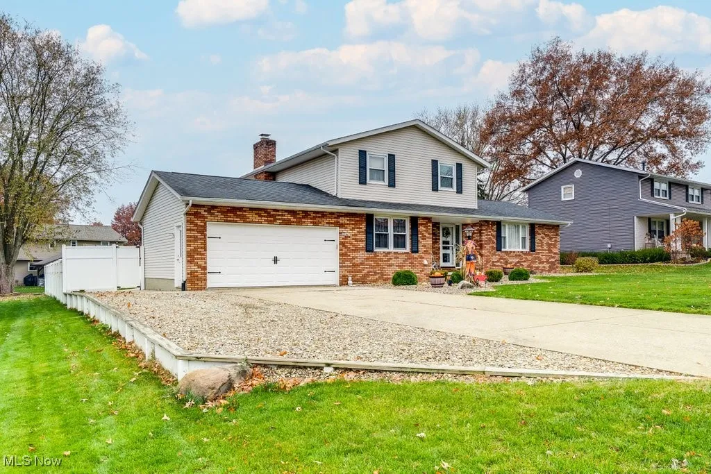 Traditional-style house featuring concrete driveway, a garage, brick siding, a chimney, and roof with shingles