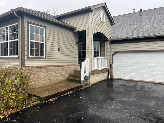 View of front of home with asphalt driveway, brick siding, an attached garage, and a shingled roof