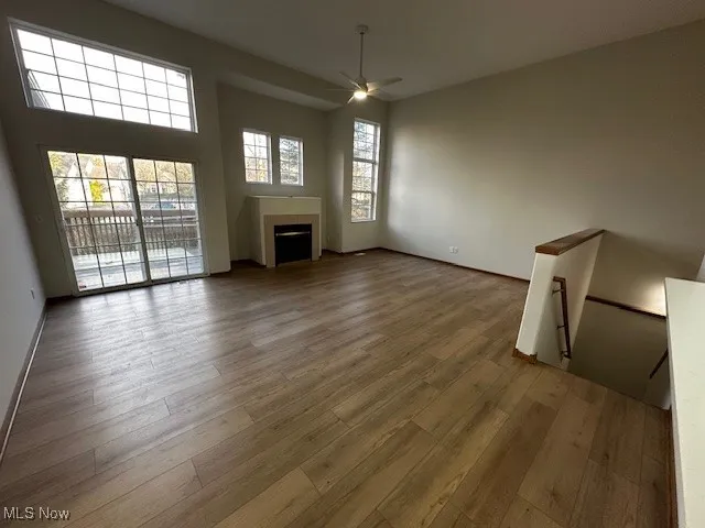 Unfurnished living room with hardwood / wood-style flooring, a fireplace, and ceiling fan