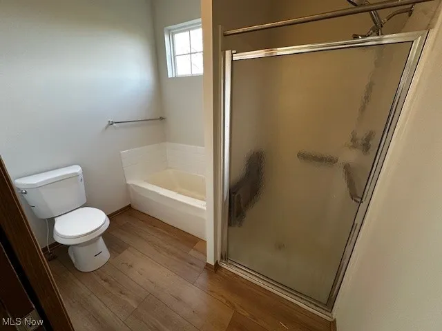 Full bathroom with a shower stall, wood finished floors, and a bath