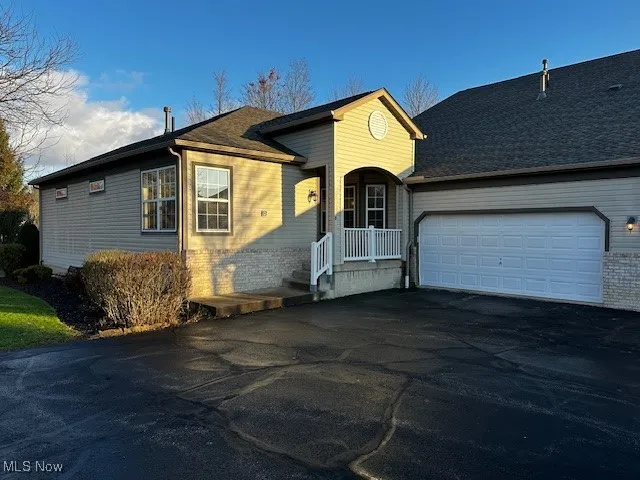 Ranch-style house featuring asphalt driveway, brick siding, and an attached garage