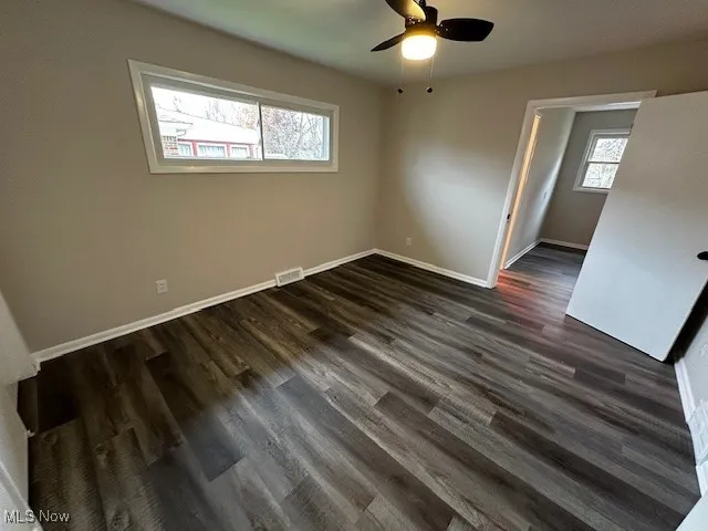 Spare room with dark wood-style floors and baseboards
