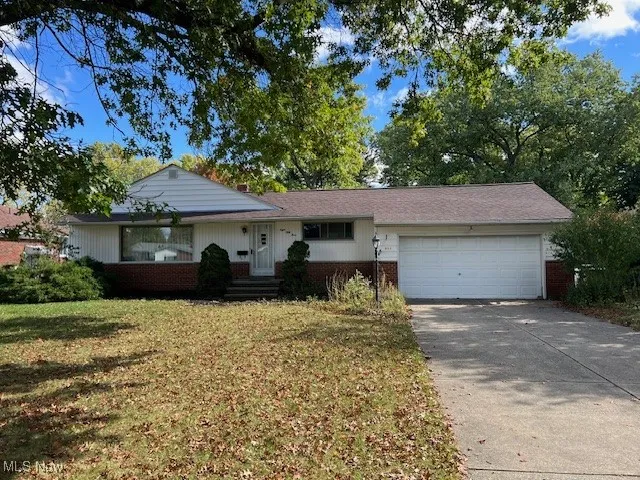 Ranch-style house featuring brick siding, driveway, a front yard, and an attached garage