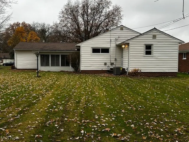 Back of property featuring a sunroom and a yard