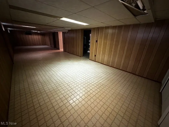 Finished below grade area featuring wooden walls, a paneled ceiling, and tile patterned floors