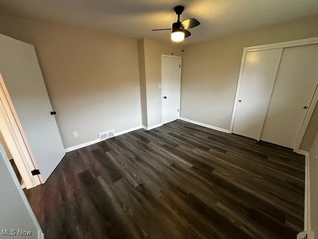 Unfurnished bedroom with dark wood-type flooring, a closet, and ceiling fan