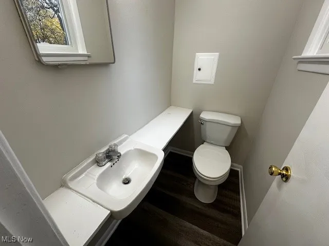 Half bathroom with toilet and wood finished floors