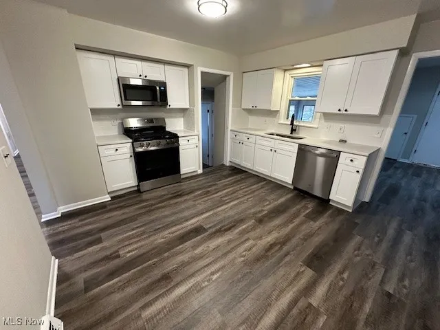 Kitchen featuring white cabinets, appliances with stainless steel finishes, and light countertops