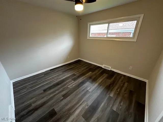 Spare room with dark wood-type flooring and ceiling fan