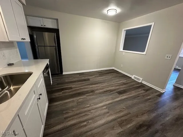 Kitchen with white cabinets, dark wood-style floors, and light stone countertops