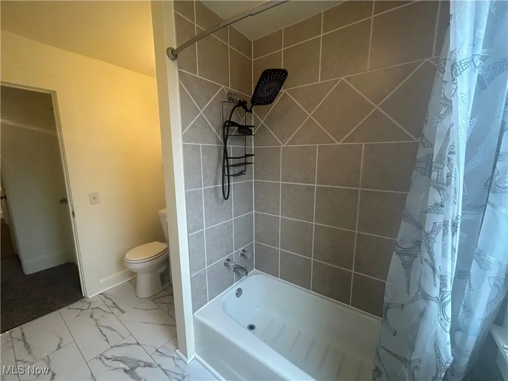 Full bathroom featuring shower / bathtub combination with curtain and marble finish floors