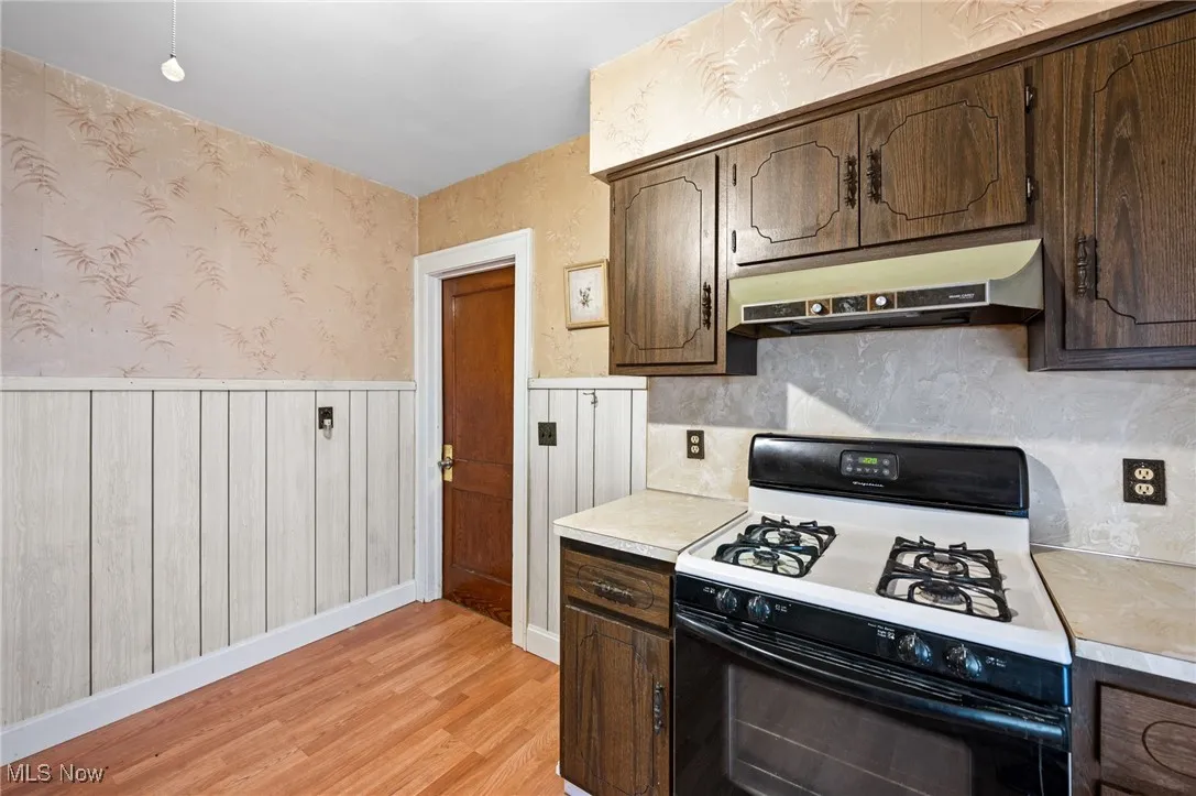 Kitchen featuring wainscoting, light countertops, and dark brown cabinetry
