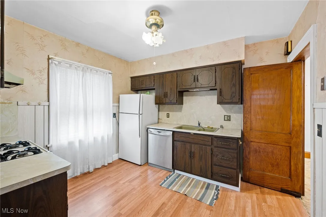 Kitchen featuring light countertops, dark brown cabinetry, and light wood-style floors