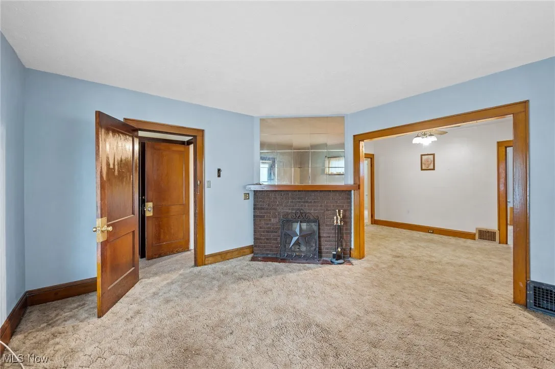 Unfurnished living room featuring a brick fireplace and carpet