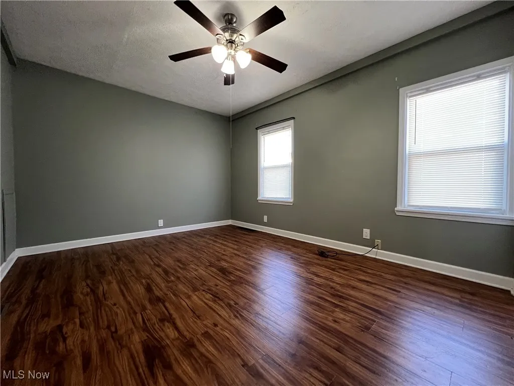 Spare room featuring dark wood-style flooring, a textured ceiling, and a ceiling fan