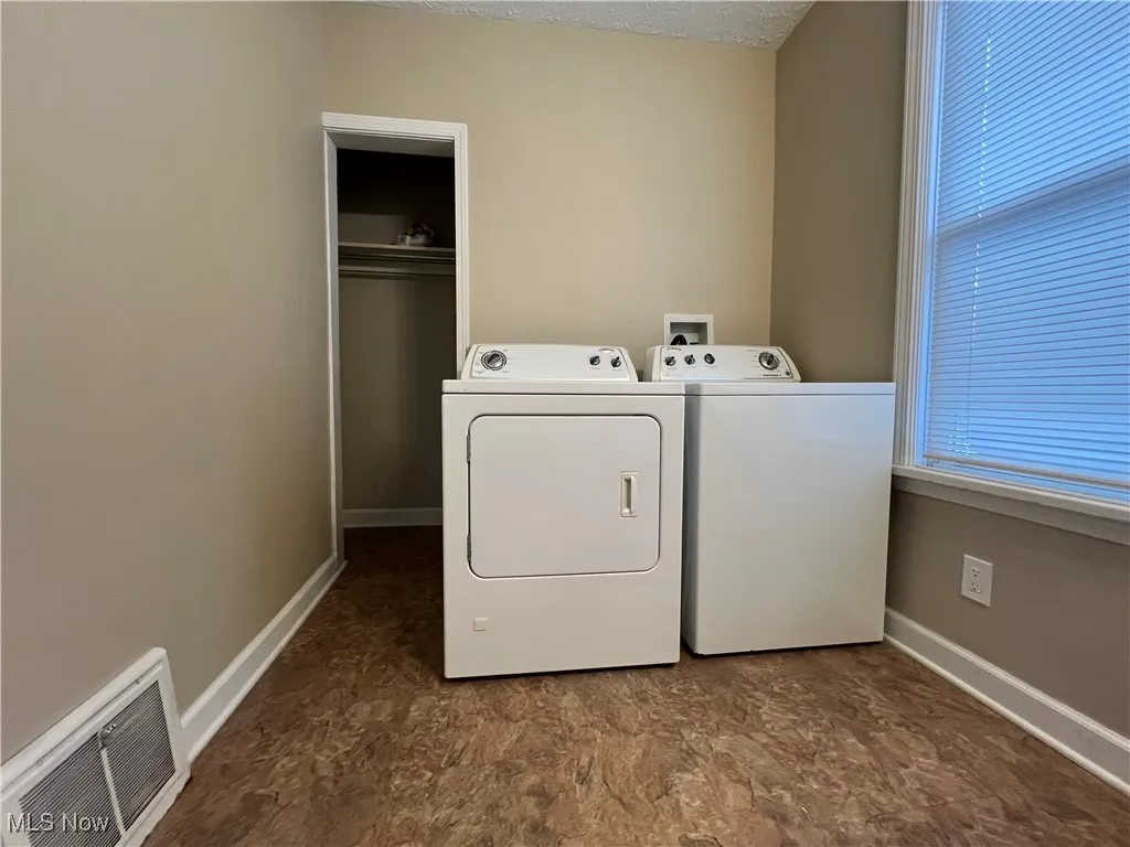 Washroom with washing machine and clothes dryer and a textured ceiling
