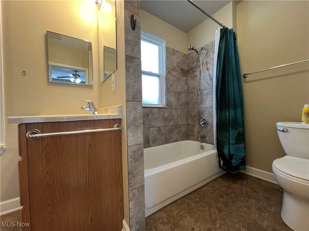 Bathroom featuring vanity and shower / bath combination with curtain