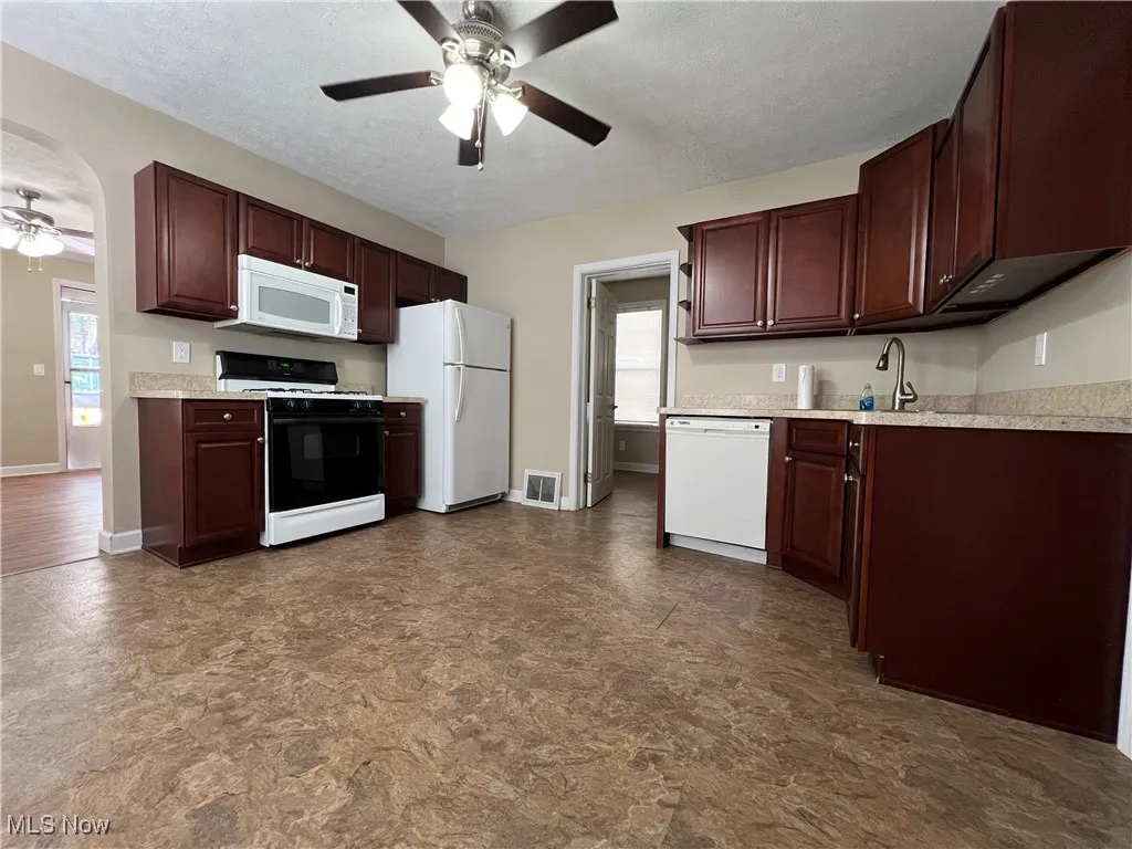 Kitchen with a ceiling fan, white appliances, light countertops, healthy amount of natural light, and a textured ceiling