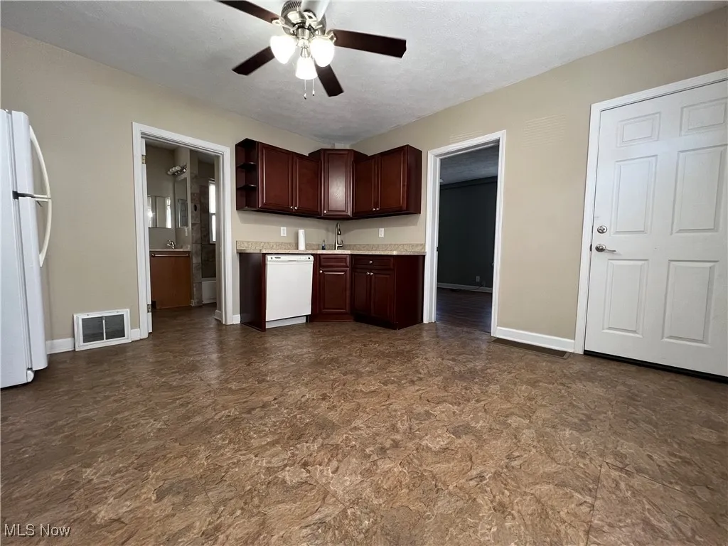 Kitchen featuring light countertops, white appliances, dark brown cabinets, ceiling fan, and open shelves