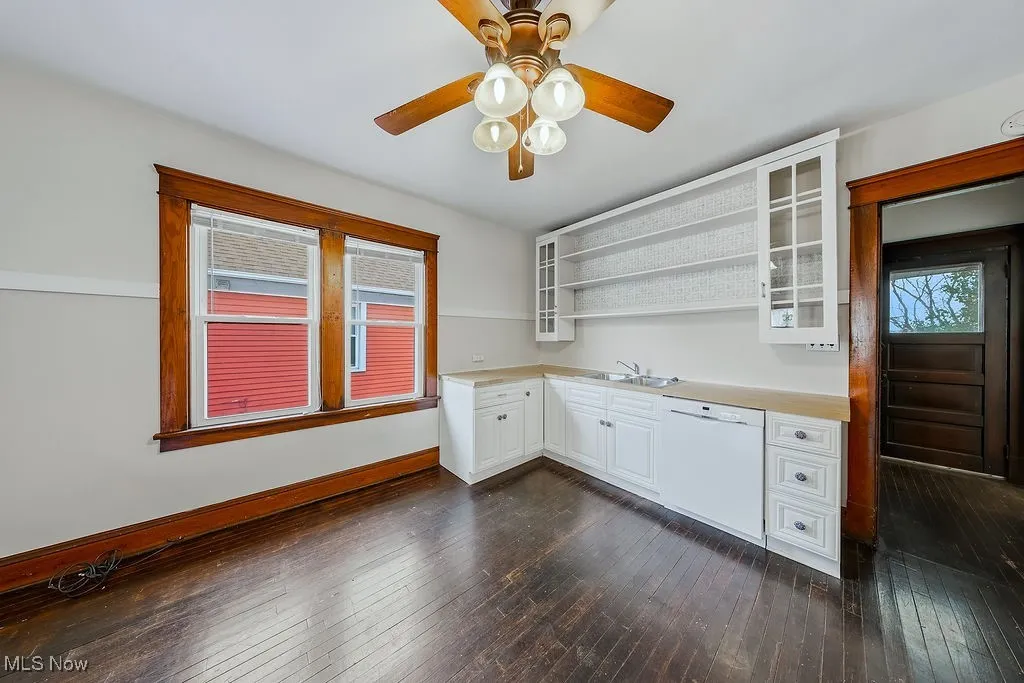 Second floor unit kitchen with white cabinets, open shelves, light countertops, white dishwasher, and dark wood-style floors