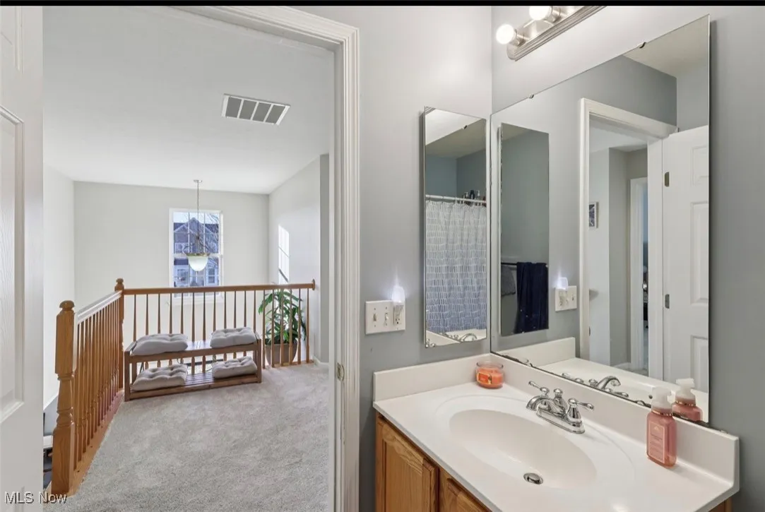 Bathroom with vanity, light carpet, a shower with shower curtain, and a chandelier