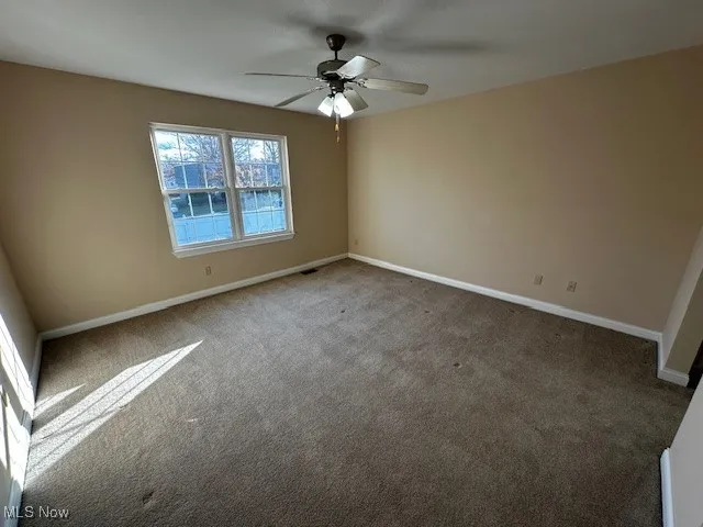 Spare room featuring carpet and ceiling fan