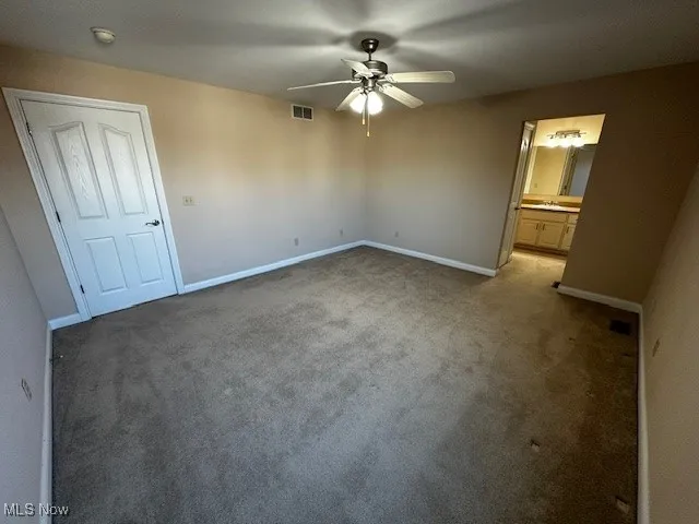Unfurnished bedroom with carpet flooring, ceiling fan, and connected bathroom