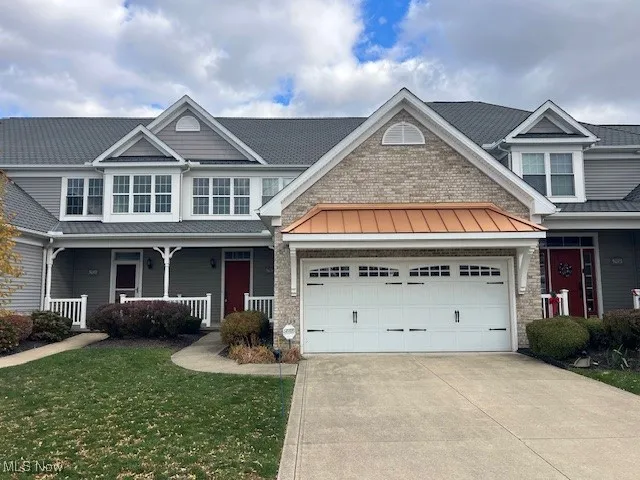 Craftsman-style home with covered porch, a standing seam roof, a front yard, a metal roof, and concrete driveway