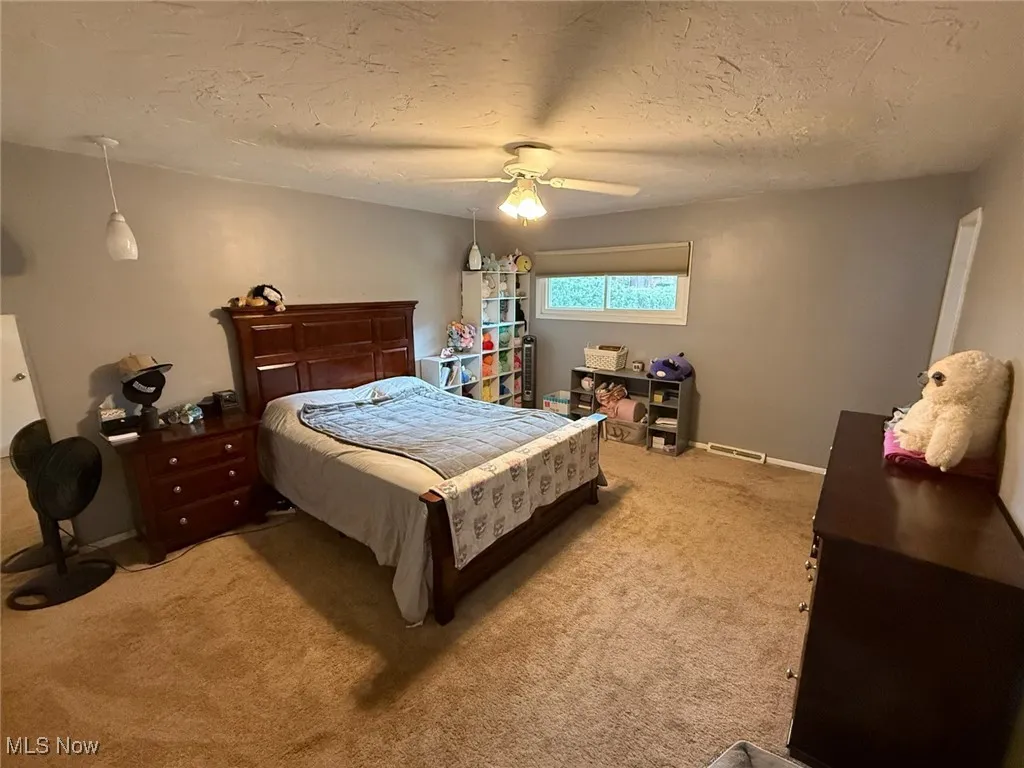 Carpeted bedroom featuring a textured ceiling and ceiling fan