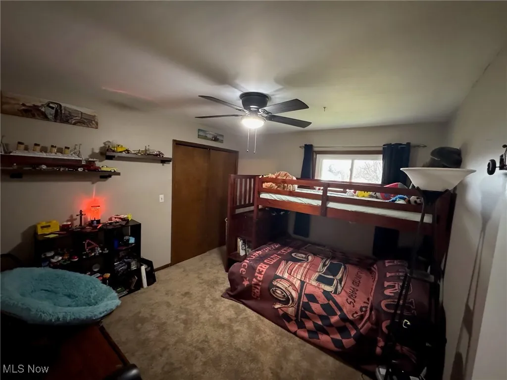 Carpeted bedroom with a ceiling fan