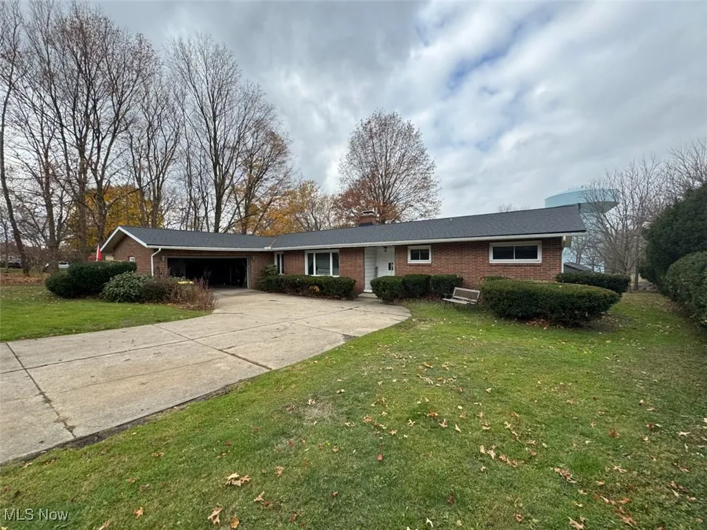 Ranch-style home with brick siding, a front lawn, driveway, and a chimney