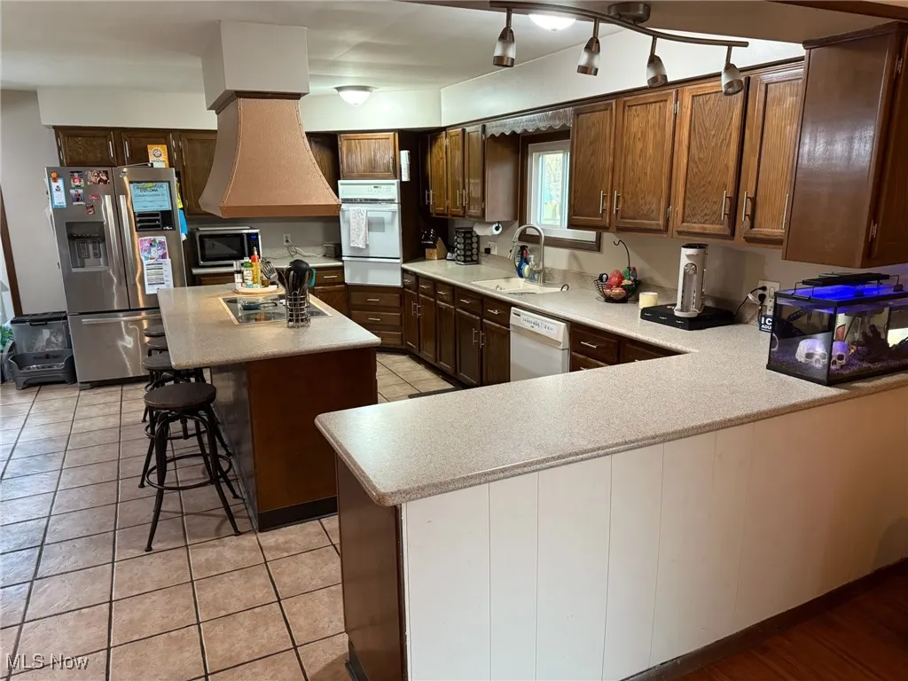 Kitchen with stainless steel appliances, a kitchen breakfast bar, light countertops, and a center island