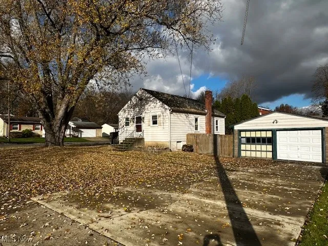 View of side of property with an outbuilding, a detached garage, and a chimney