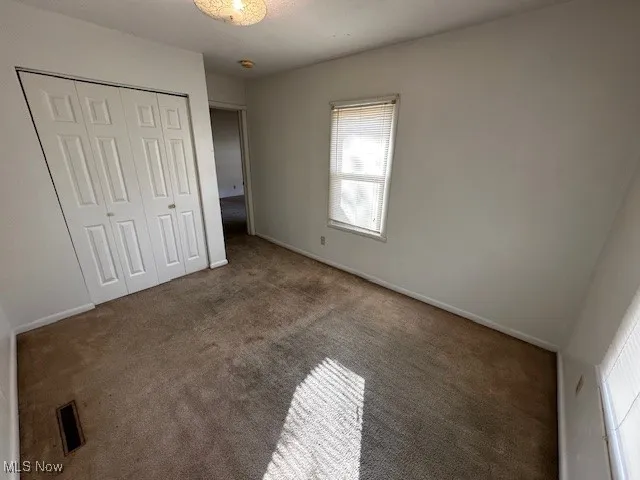 Unfurnished bedroom with carpet flooring and a closet