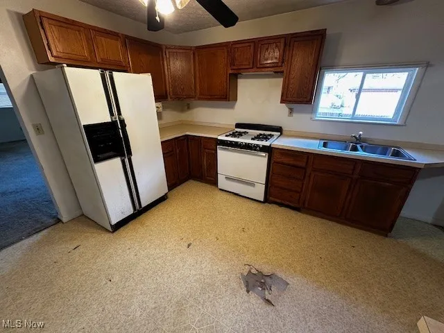 Kitchen with light flooring, white appliances, light countertops, a textured ceiling, and ceiling fan