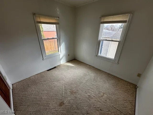 Carpeted empty room with healthy amount of natural light and crown molding