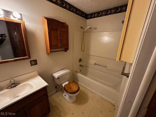 Full bathroom with vanity, bathing tub / shower combination, and a textured ceiling