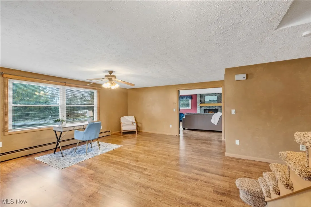 Office with healthy amount of natural light, a textured ceiling, a ceiling fan, and light wood finished floors
