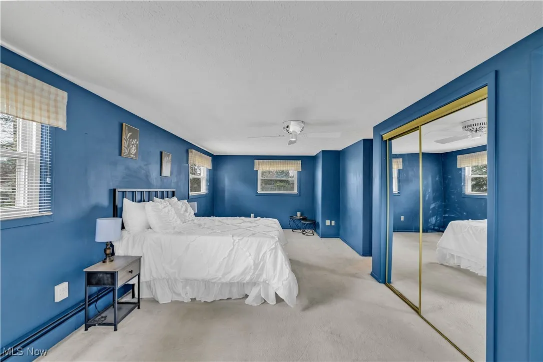 Bedroom with a closet, carpet flooring, ceiling fan, and a textured ceiling