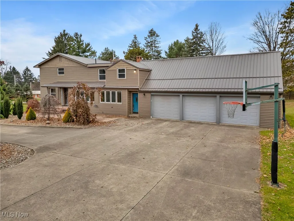 Traditional home featuring concrete driveway, a garage, a chimney, and a metal roof