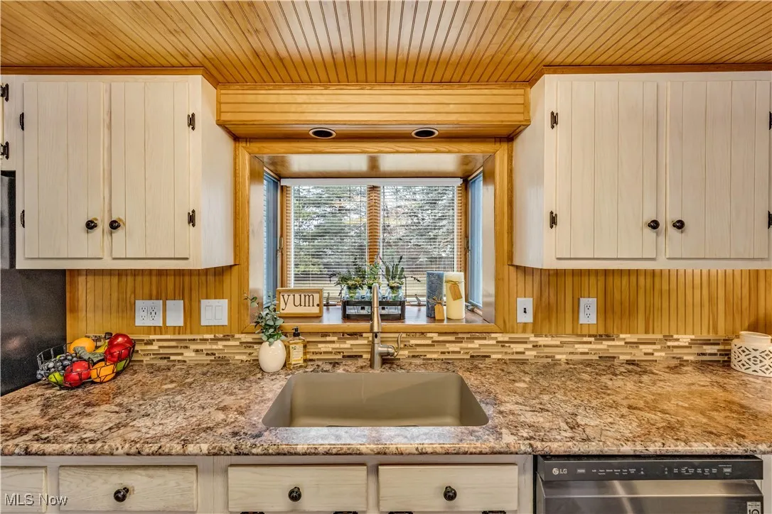 Kitchen featuring dishwasher, wood ceiling, and light stone counters