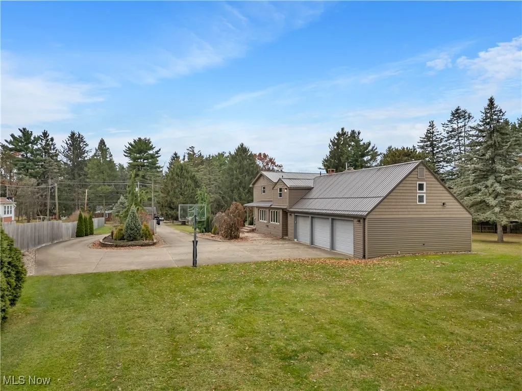 View of yard with a garage, driveway, and view of scattered trees