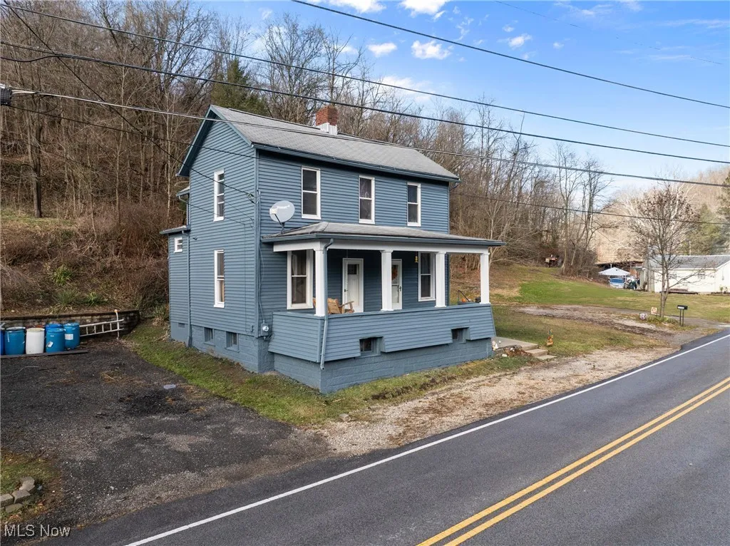 View of front facade featuring a chimney and a porch