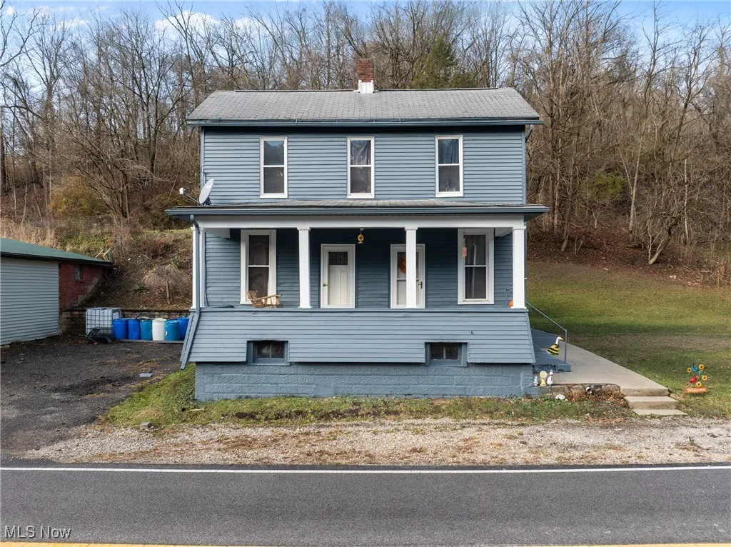 View of front facade featuring a porch and a chimney