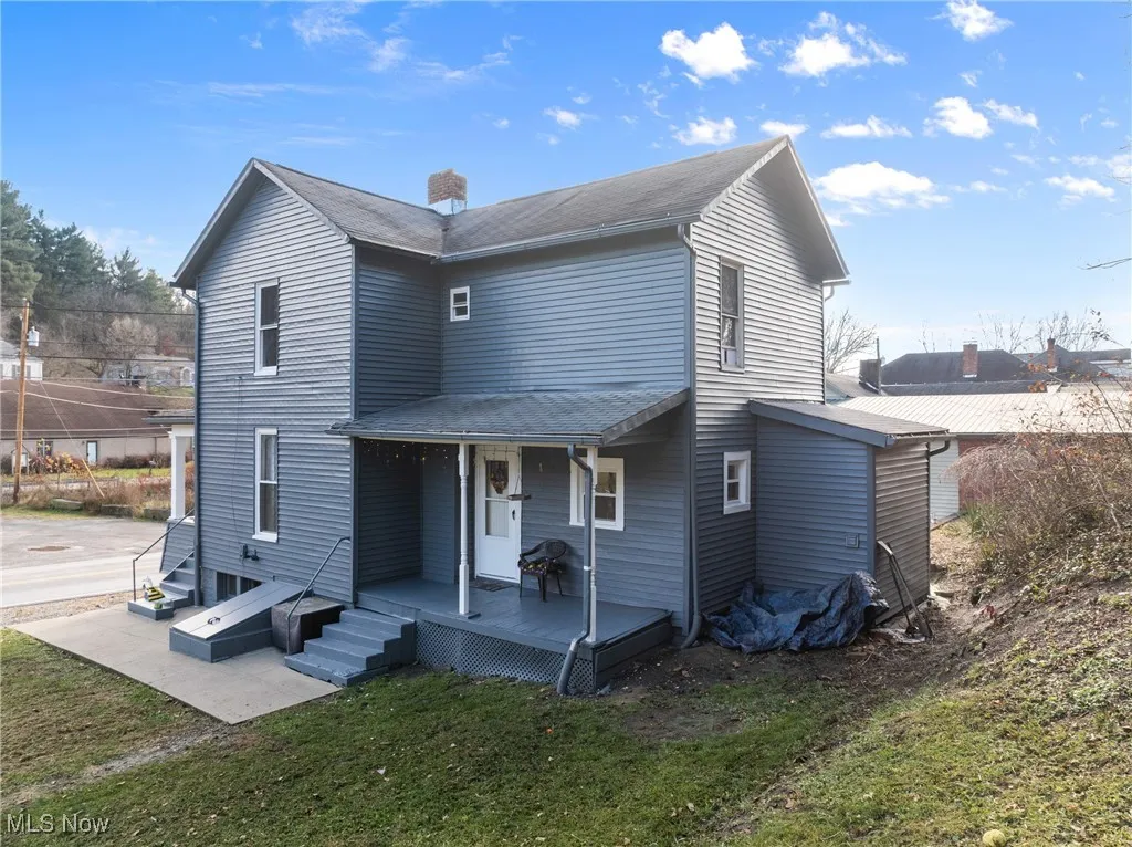 Rear view of house featuring a chimney and a yard