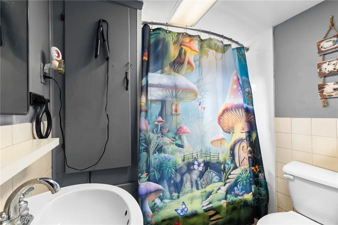 Bathroom with curtained shower and tile walls