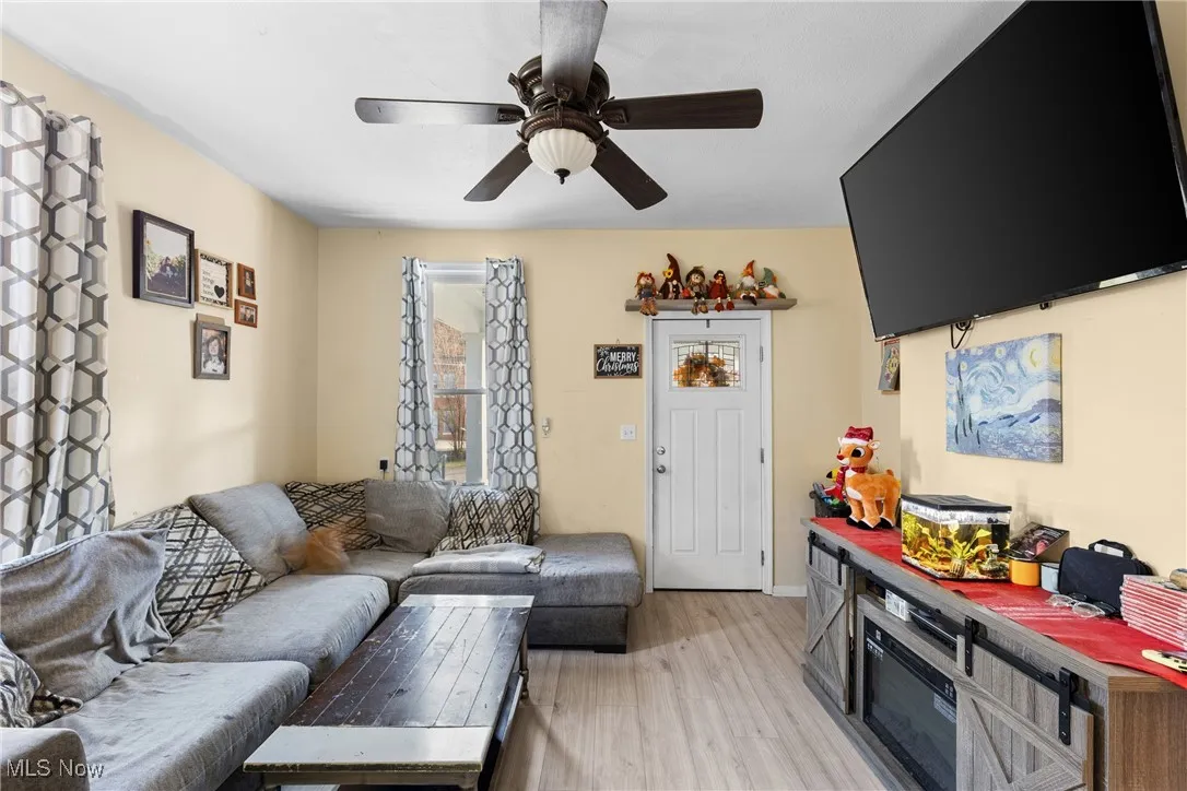 Living room with light wood-type flooring and a ceiling fan