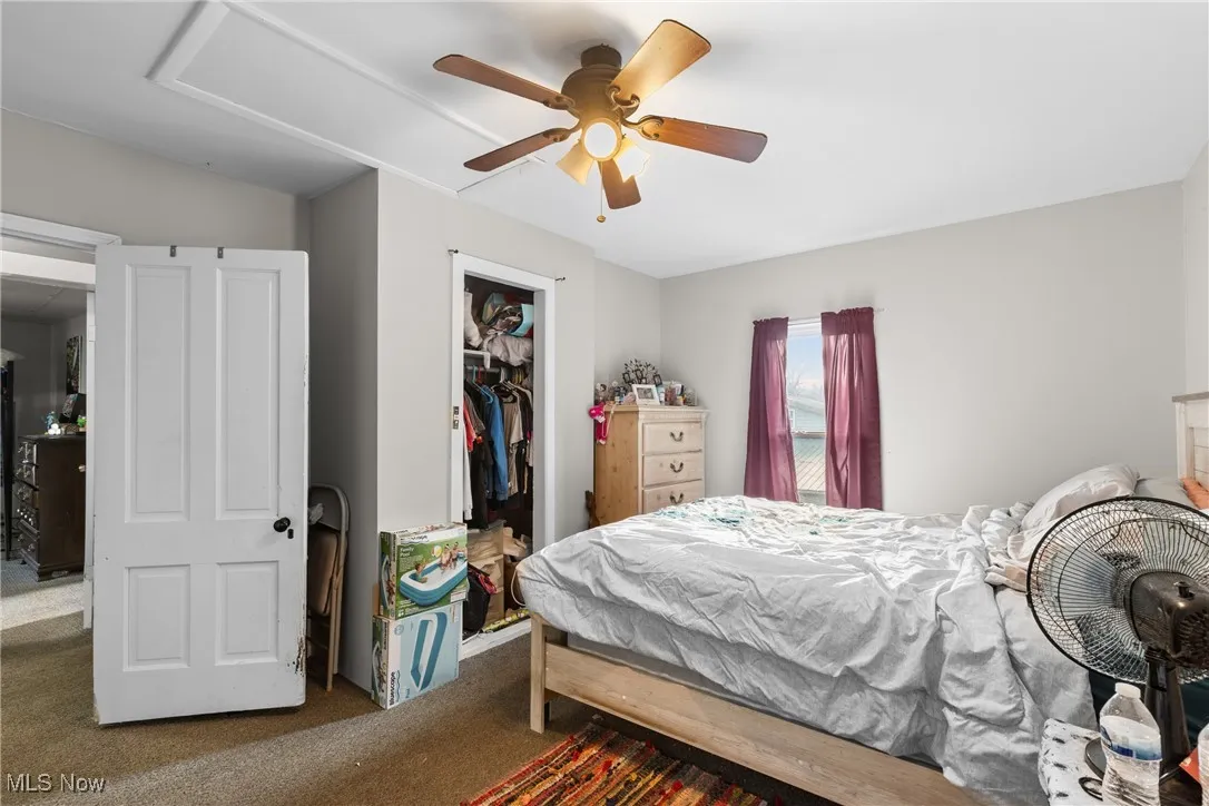 Bedroom with carpet floors, a walk in closet, and a ceiling fan